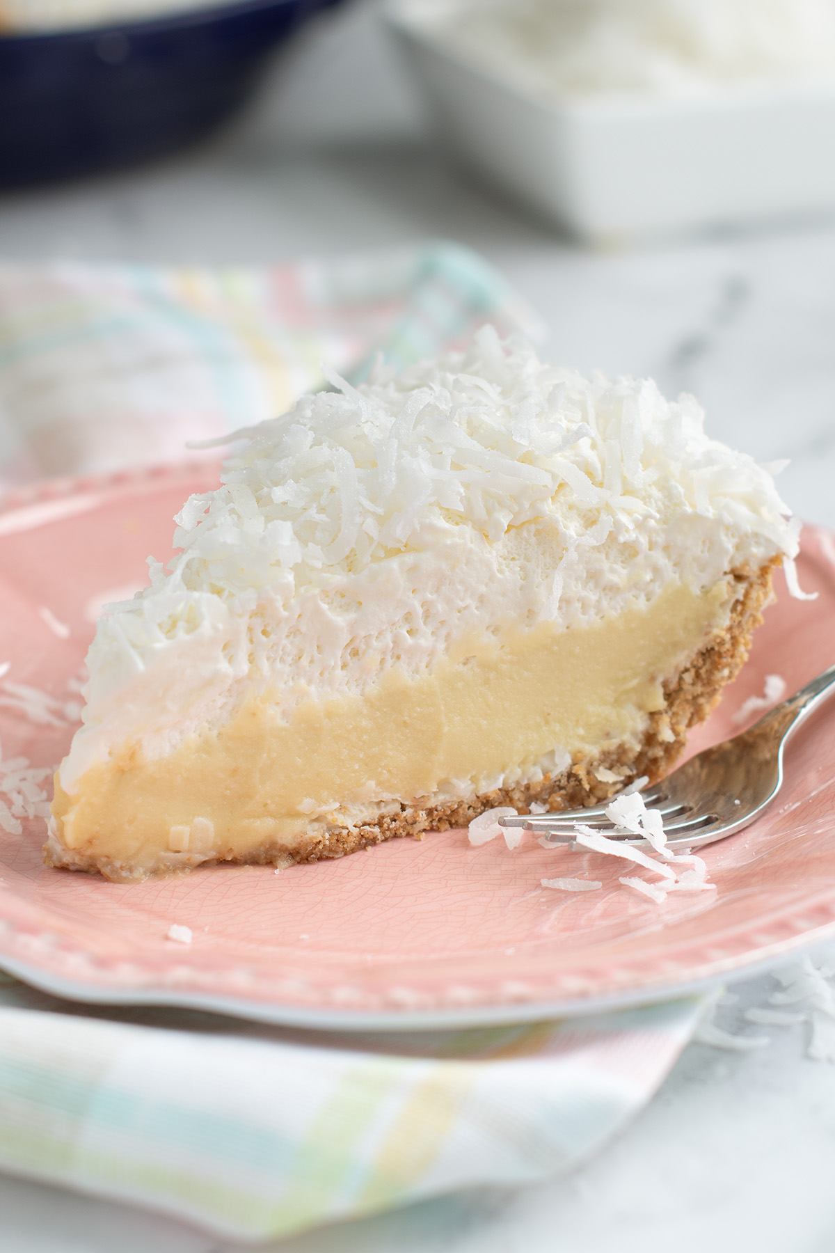 a slice of coconut cream pie on a pink plate.